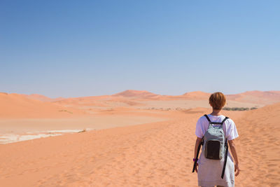 Rear view of woman standing on sand dune