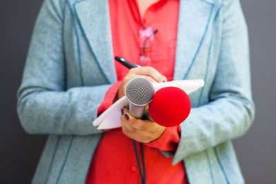 Close-up of journalist holding microphones while writing in book