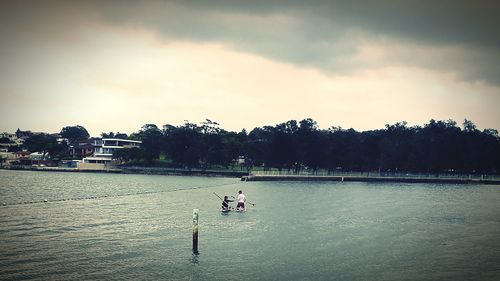 Boat sailing in river against cloudy sky