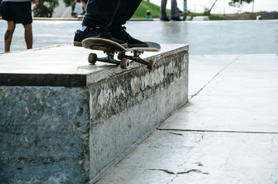 Low section of man skateboarding on footpath