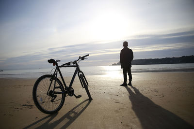 Rear view of man standing on calm beach