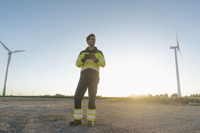 Engineer standing in rural landscape at a wind farm holding tablet