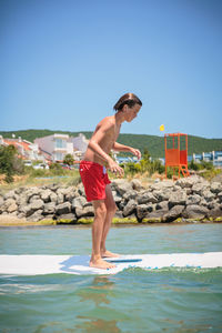 Handsome teenage boy having fun floating on a swim board