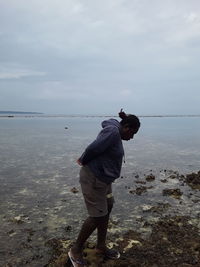 Man standing at beach against sky