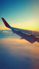 Airplane wing against sky during sunset
