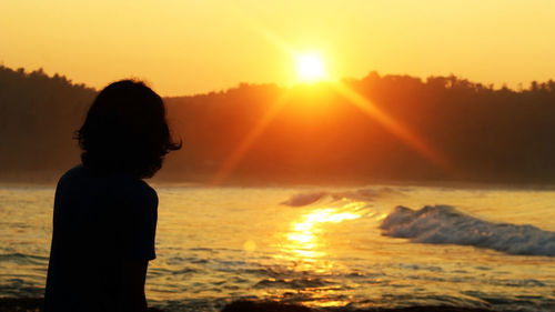 Silhouette man looking at sea against sky during sunset