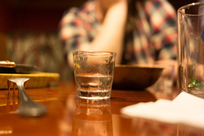 Close-up of drinking glass with fork and plate on table