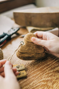 Cropped hands of woman holding wooden heart shape at table