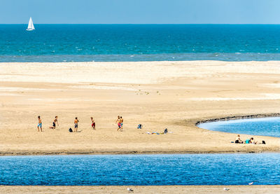 High angle view of children playing on sand at beach during sunny day