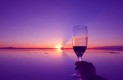 Wineglass against sky during sunset