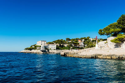 Houses by sea against clear blue sky