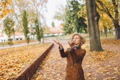 Young woman playing with autumn leaf at park