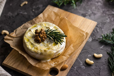 Baked camambert on cutting board with walnut and cashew nuts on grey concrete background 