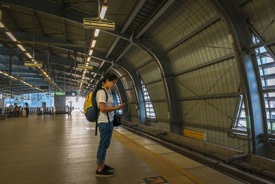 Woman using mobile phone while standing on railroad station platform