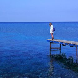 Full length of woman standing on pier by sea