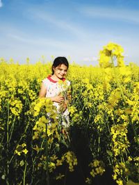 Portrait of smiling girl standing amidst yellow flowering plants