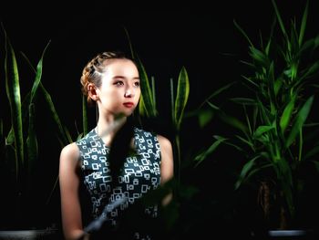 Portrait of a beautiful young woman standing against plants