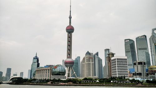Communications tower in city against sky