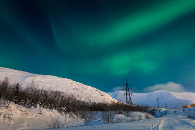 Snow covered landscape against sky at night