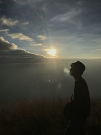 Silhouette man smoking on sunrise