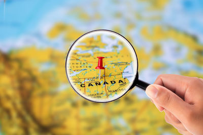 Close-up of person hand holding magnifying glass over map