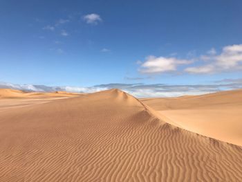 Sand dunes in desert against sky