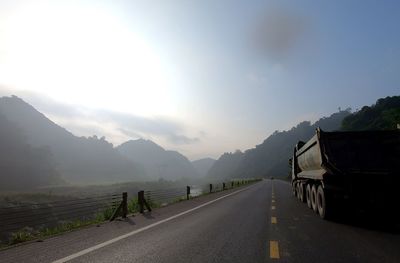 Empty road by mountains against sky