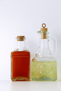Close-up of oil in bottles on table against white background