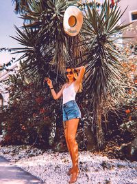 Full length of young woman standing by tree