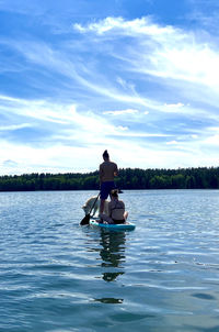 Man and woman sitting on boat in lake against sky