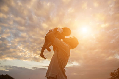 Low angle view of woman standing against sky during sunset