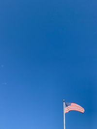 Low angle view of flag against blue sky