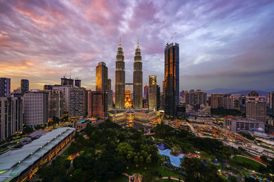 View of illuminated cityscape against cloudy sky