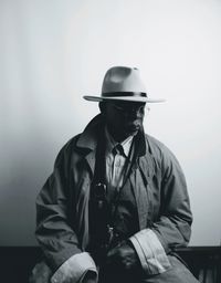 Man wearing hat sitting against wall