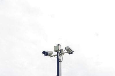 Low angle view of security camera against sky