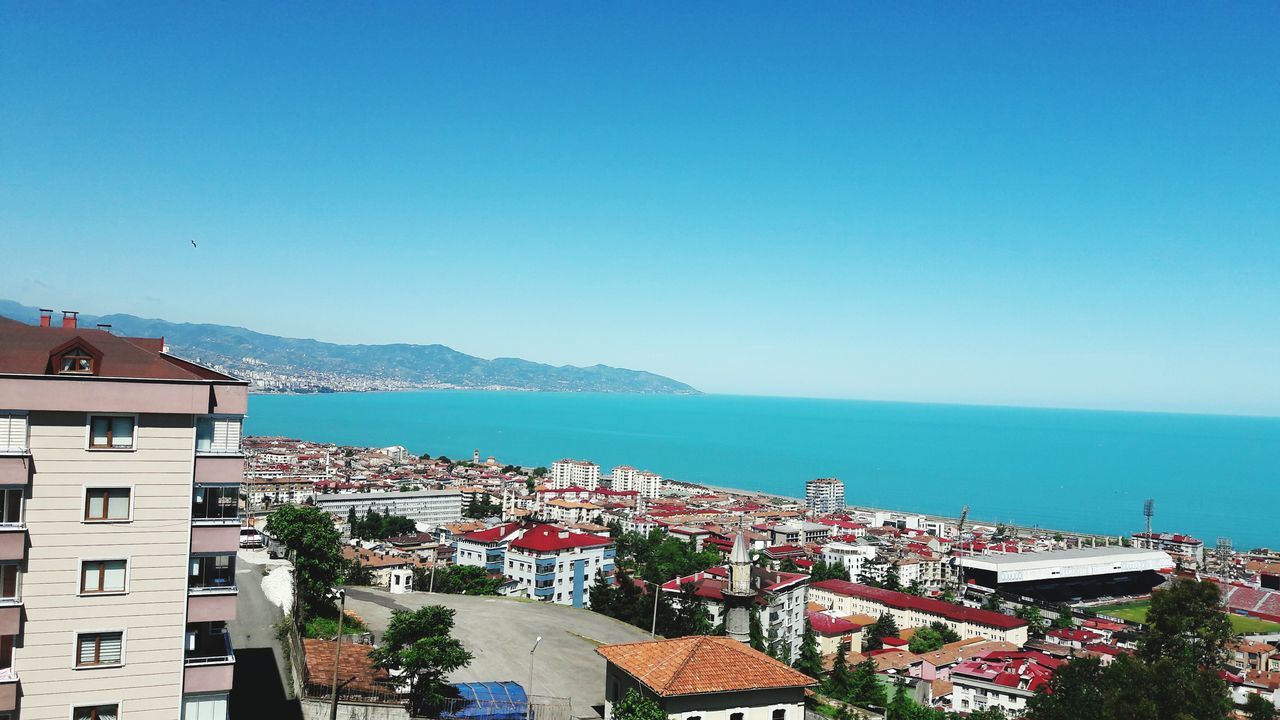 architecture, building exterior, built structure, sea, clear sky, mountain, water, day, town, copy space, house, residential building, high angle view, outdoors, blue, no people, horizon over water, scenics, sky, cityscape, nature, beauty in nature, city