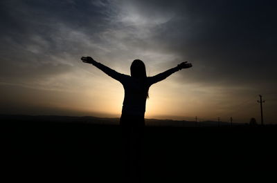 Silhouette woman standing on field against sky during sunset