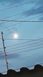 Low angle view of electricity pylon against blue sky