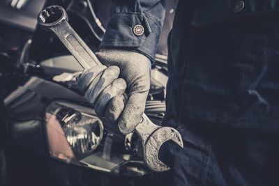 Midsection of worker holding wrench