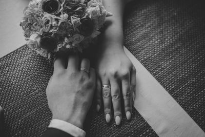 Midsection of newlywed couple holding hands on table