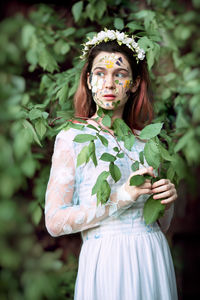 Teenage girl wearing dress standing against plants