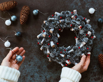 Cropped hand holding christmas decoration on table