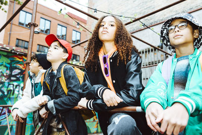 Multiracial male and female friends leaning on railing while hanging out on weekend