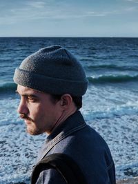 Close-up of young man wearing knit hat while standing at beach