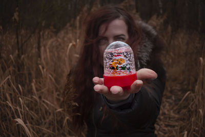 Portrait of woman holding ice cream on field