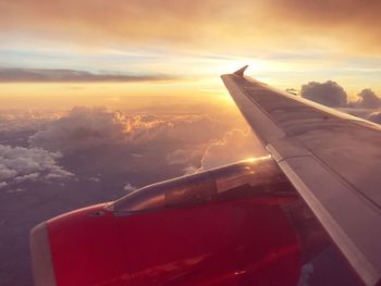 Close-up of airplane wing against sky during sunset