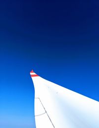 Low angle view of airplane flying against clear blue sky