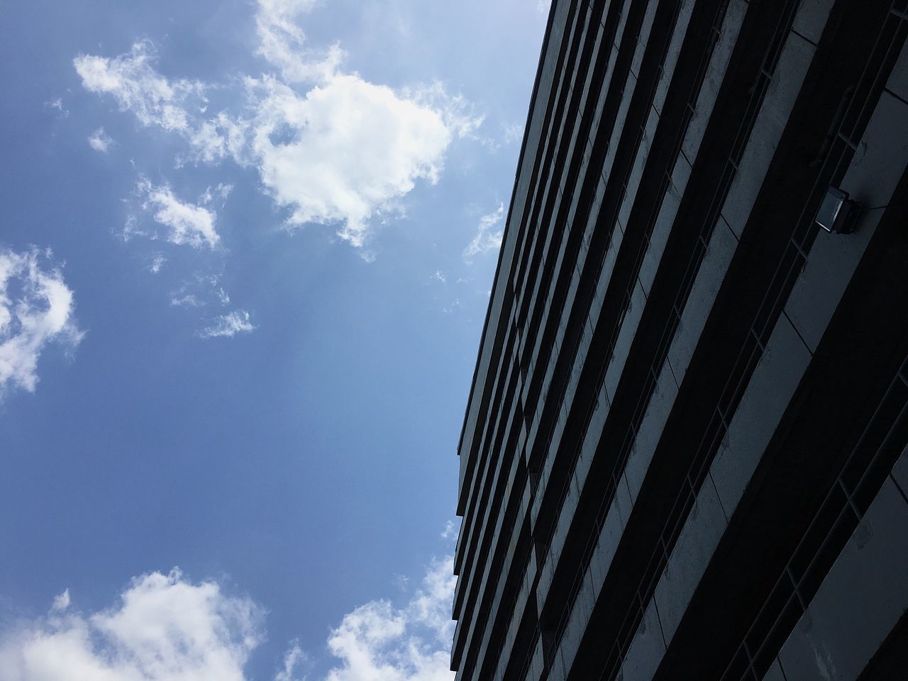 LOW ANGLE VIEW OF MODERN BUILDING AGAINST BLUE SKY
