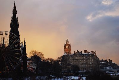 Silhouette edinburgh cathedral by clock tower in city against sky during sunset