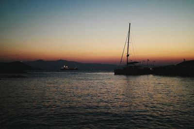 Silhouette sailboats moored on sea against sky during sunset